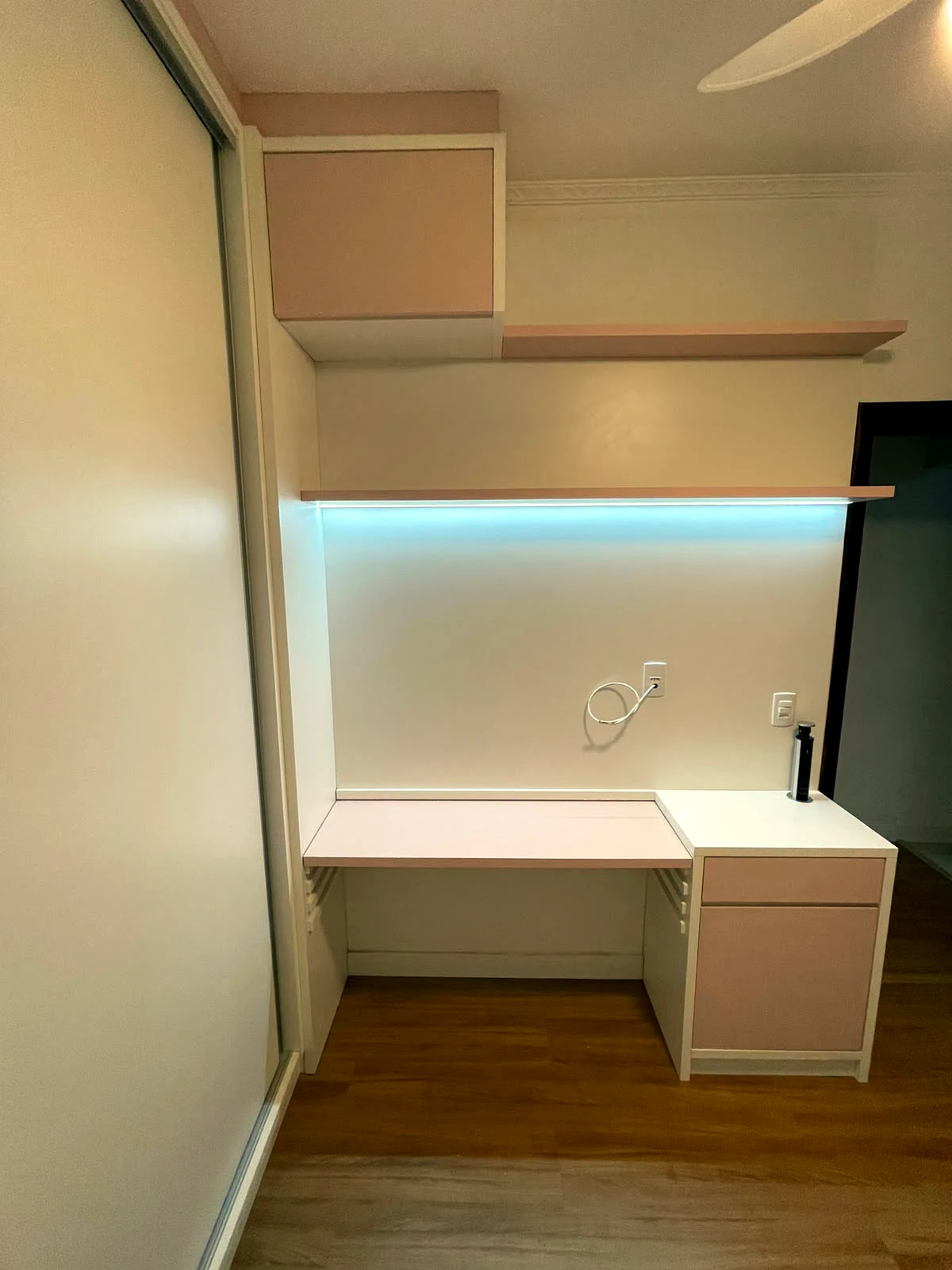 Home office delicado em rosa pastel com prateleiras e mesa
